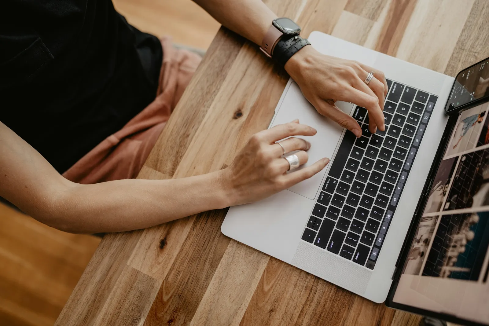 A person typing on a laptop on a wooden desk