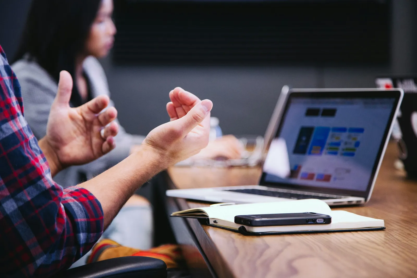 Hands gesture beside a laptop during a team meeting.